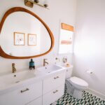 A white bathroom with white appliances and a large circular mirror.